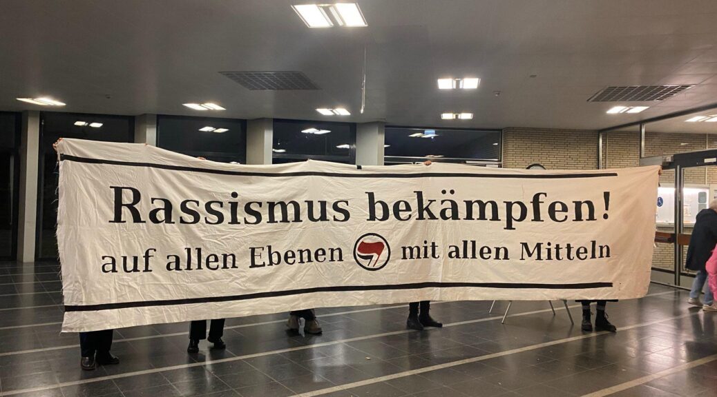 Auf dem Bild ist ein Banner mit der Aufschrift "Rassismus bekämpfen. Auf allen Ebenen. Mit allen Mitteln." Das Banner wurde als antifaschistischer Protest gegen rassistischer Mobilisierung im Hamburg-Haus in Eimsbüttel gezeigt, wo eine Informationsveranstaltung zu einer Unterkunft in der Bismarckstraße stattfand.